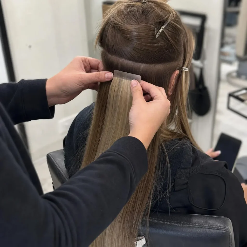 hairstylist applying tape in hair extensions correctly