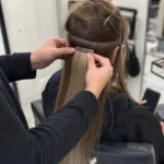 hairstylist applying tape in hair extensions correctly