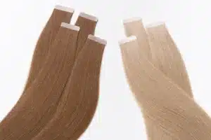 Brown and beige-blonde tape-in hair extensions arranged to show the adhesive tab finish.