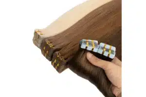 Brunette and blonde tape in extension pieces held with the attachment tabs visible.