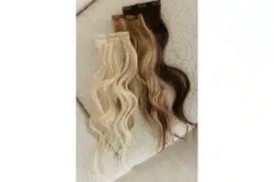 Blonde and brunette wavy clip in extension pieces arranged on a neutral surface.