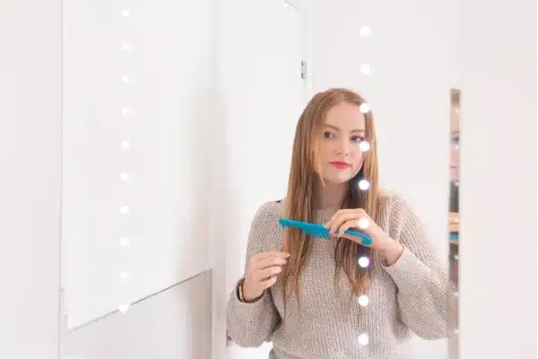 Woman working through long hair with a wide-tooth comb.