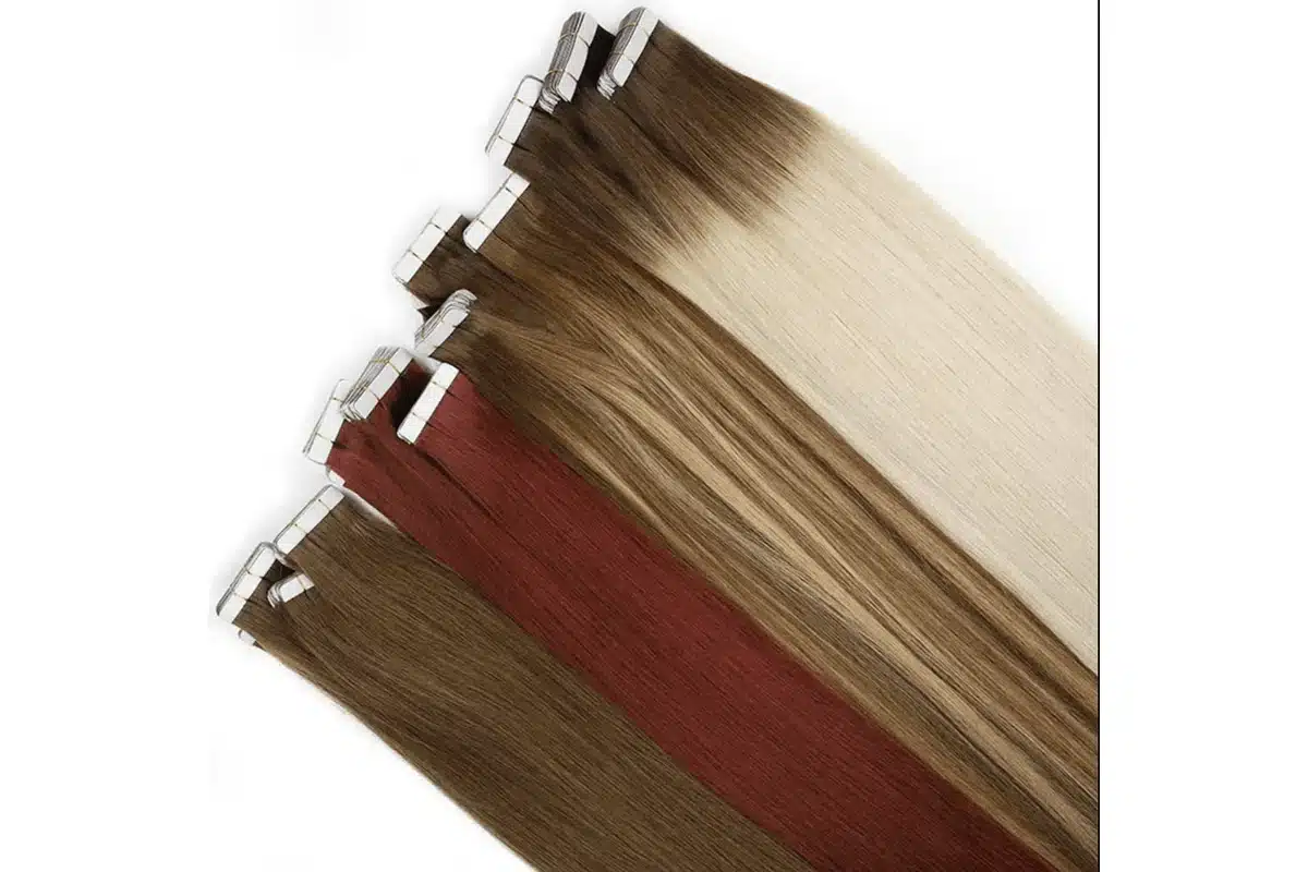 Brown, auburn, blended, and rooted blonde tape in hair extensions arranged diagonally with attachment tabs visible.