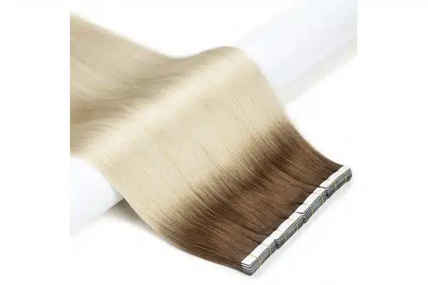 Rooted blonde tape in extensions showing a brown upper section that blends into pale blonde lengths.