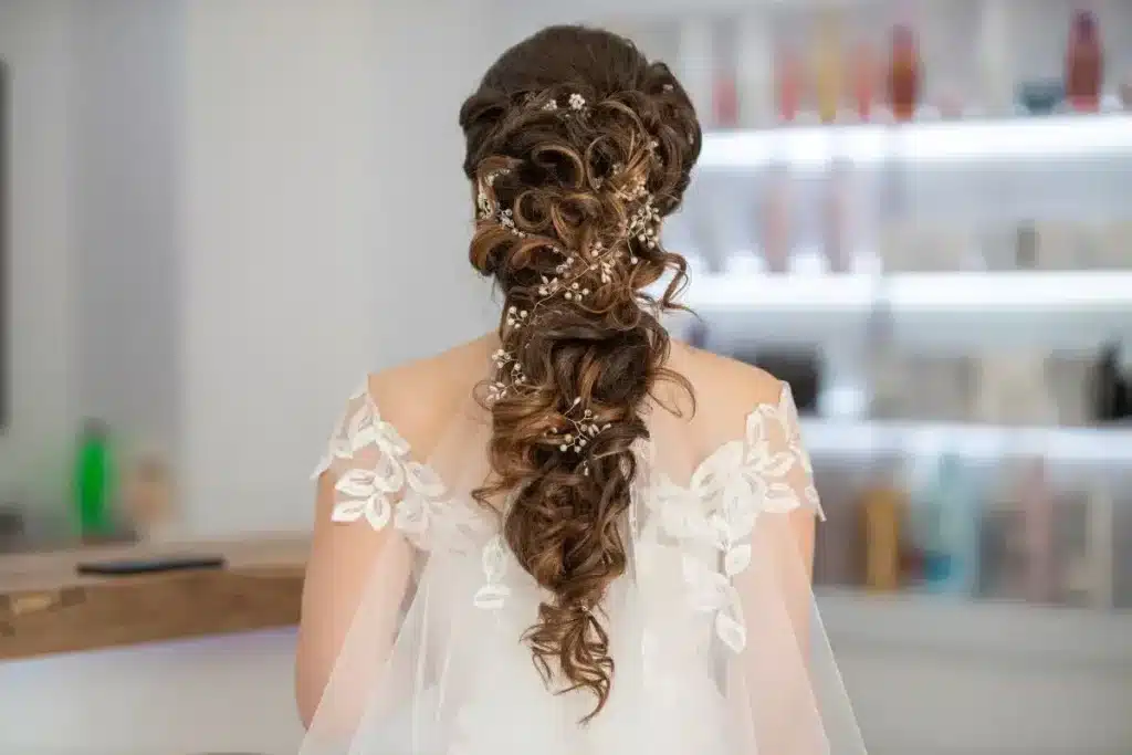 A brown-haired model shows a braided low hairstyle from behind.