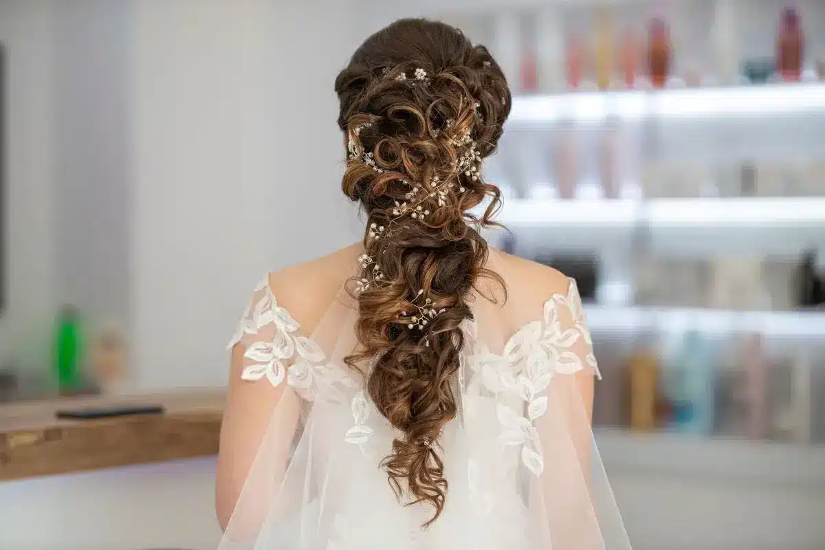 A brown-haired model shows a braided low hairstyle from behind.